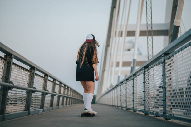 istock Young woman riding her longboard on the bridge 1372867045