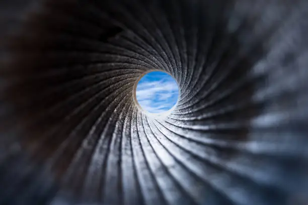 Photo of View through cannon barrel on blue sky with clouds