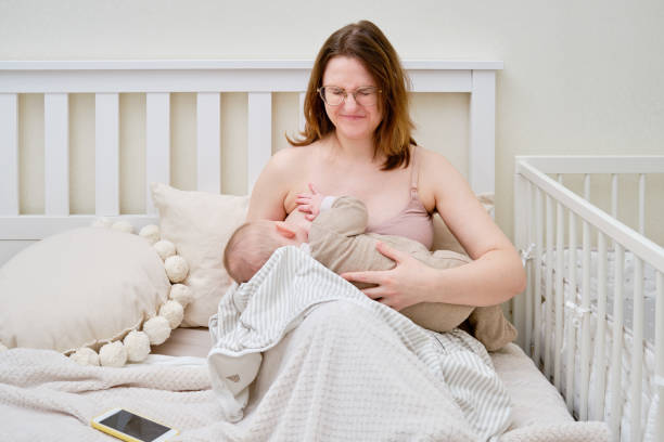 Pain and problems in a woman while breastfeeding a baby. Mother experiences discomfort while breastfeeding Pain and problems in a woman while breastfeeding a baby. Mother experiences discomfort while breastfeeding Breastfeeding stock pictures, royalty-free photos & images