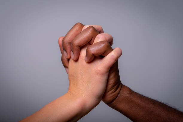istock Two hands, one white and one black, shake. Concept of multi-ethnicity and racism 1372874895