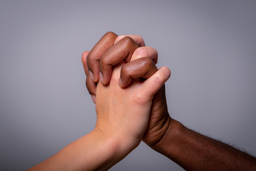 Two hands, one white and one black, shake. Concept of multi-ethnicity and racism