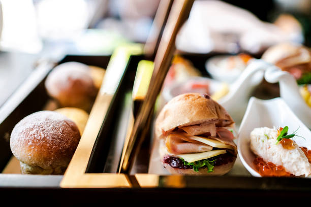 Mini hamburger with bun, sliced ham, cheese, lettuce and raspberry jam that served for afternoon tea.