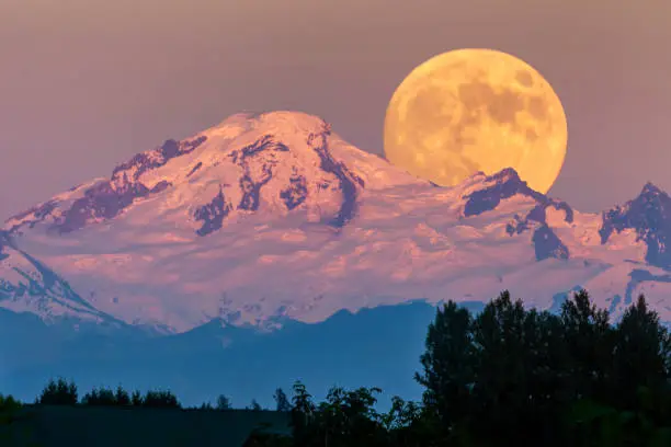 snow mountain with full moonrise at sunset