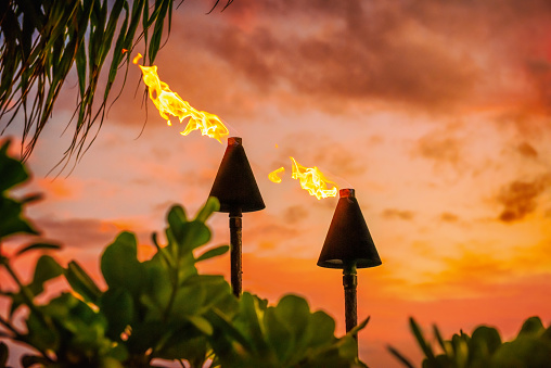 Hawaii luau party Maui fire tiki antorchas con llamas abiertas ardiendo al atardecer nubes del cielo por la noche. Antecedentes de vacaciones de viajes culturales hawaianos. photo