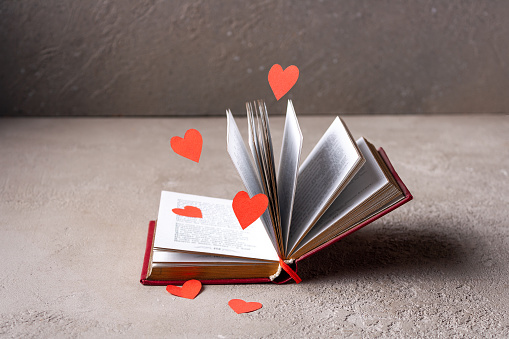 red paper hearts fly around an open book