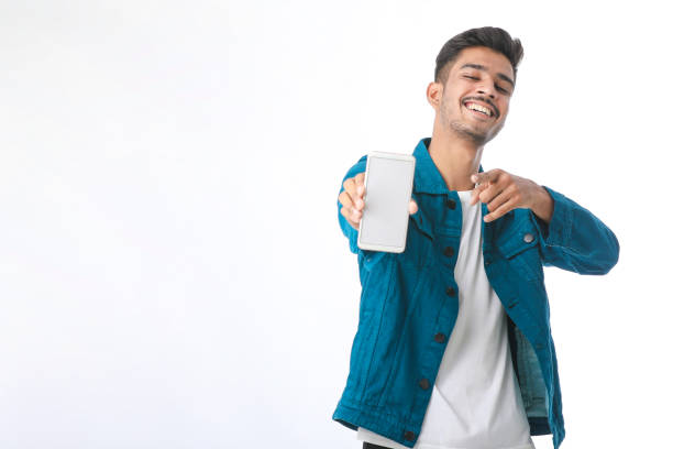Young indian man showing smartphone screen on white background.