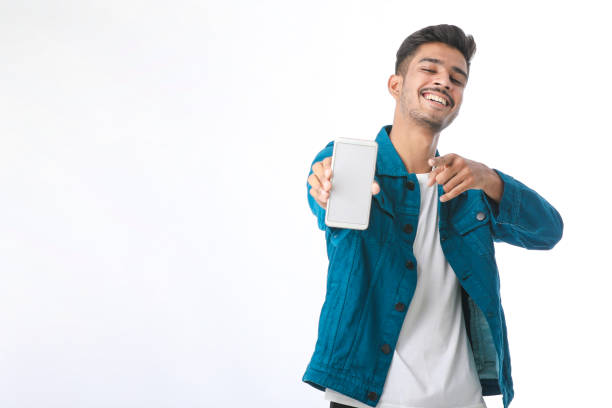 young indian man showing smartphone screen on white background. - thumps up imagens e fotografias de stock