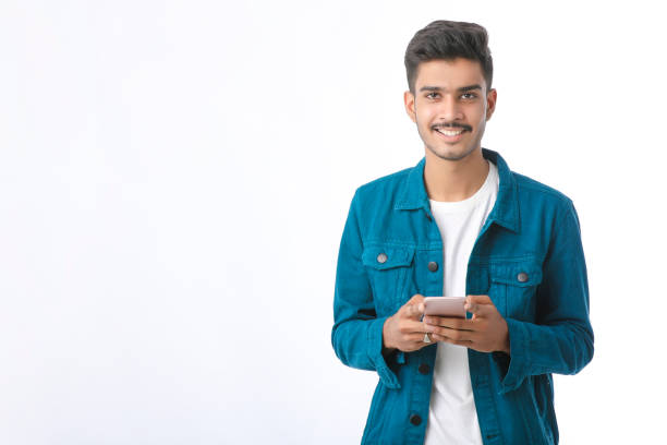 young indian man using smartphone and giving expression on white background. - thumps up imagens e fotografias de stock