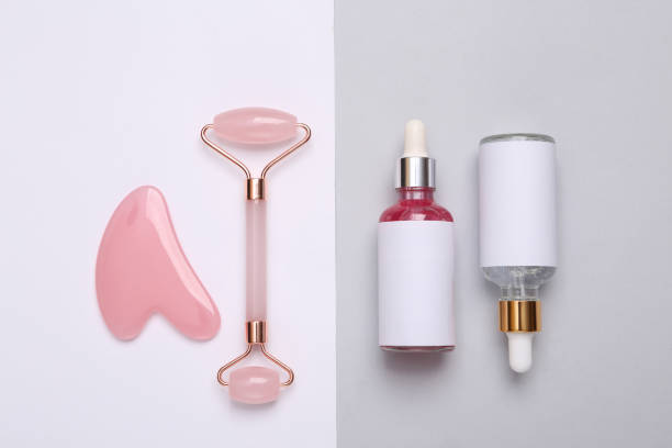 istock Beautiful composition of mockup serum bottle, pink face roller on gray white background. Creative trendy beauty flat lay 1372906943