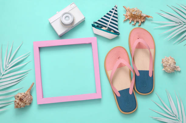 istock Summer layout. Beach accessories with white palm leaves and pink blank frame for text on turquoise background 1372907583