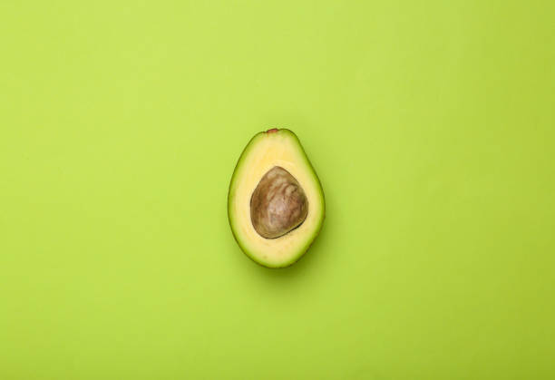 istock Half ripe avocado fruit with bone on green background 1372907597