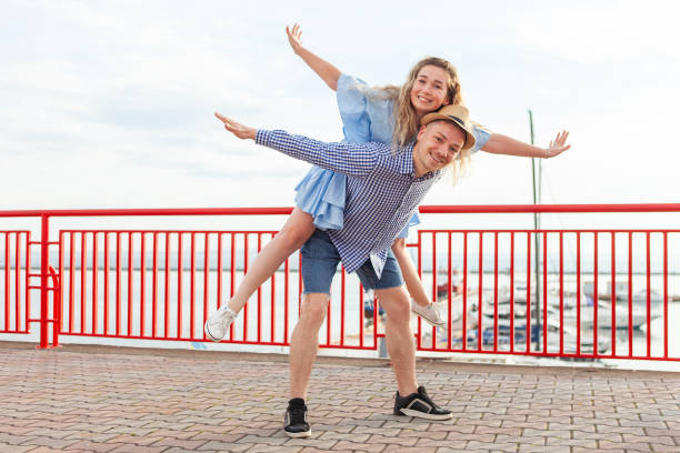 istock Enjoying every moment together. Young couple in love having fun outdoors while handsome man giving his girlfriend piggy back ride. Romantic, love concept 1372911343
