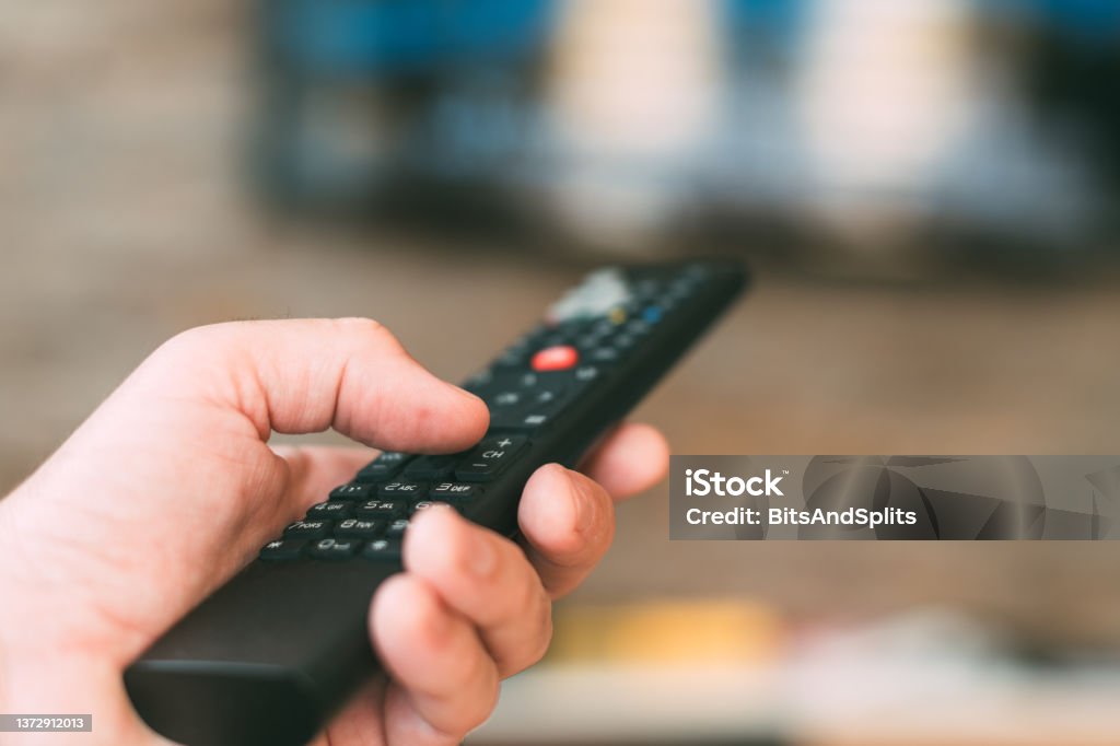 Male hand holding television remote controller Male hand holding television remote controller, close up with selective focus Video On Demand Stock Photo