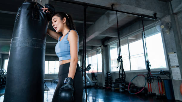 Asian sportswoman in sportswear wearing boxing gloves do boxing exercise at gym. Strong Asian athletic woman in sportswear wearing boxing gloves do workout exercise punching boxing bag at fitness gym. Healthy fit and firm female do sport training and bodybuilding at sport club. women boxing sport exercising stock pictures, royalty-free photos & images