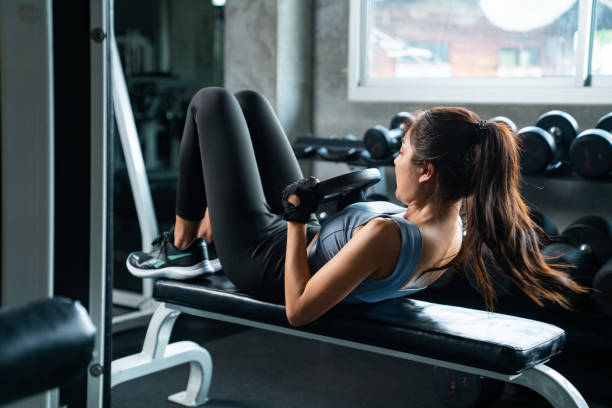 азиатская спортсменка женщина абдоминальная тяжелая атлетика сидят упражнения в фитнес-зале. - weight bench стоковые фото и изображения