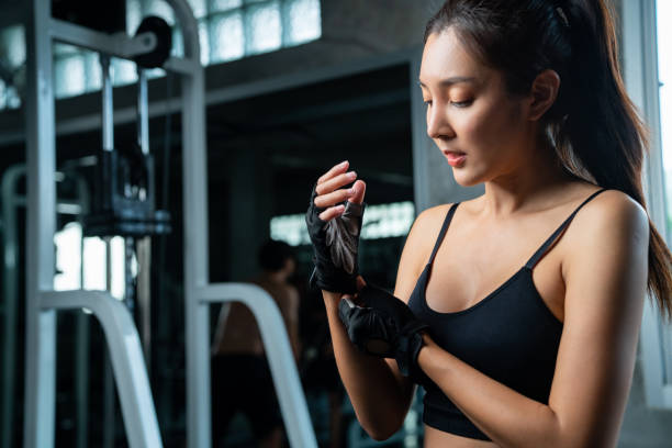 donna atletica asiatica in abbigliamento sportivo che indossa guanti sportivi prima dell'esercizio di allenamento in palestra fitness. - women weight bench exercising weightlifting foto e immagini stock