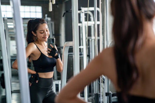 istock Asian athletic woman using mobile phone taking selfie on mirror while workout exercise at fitness gym. 1372915909