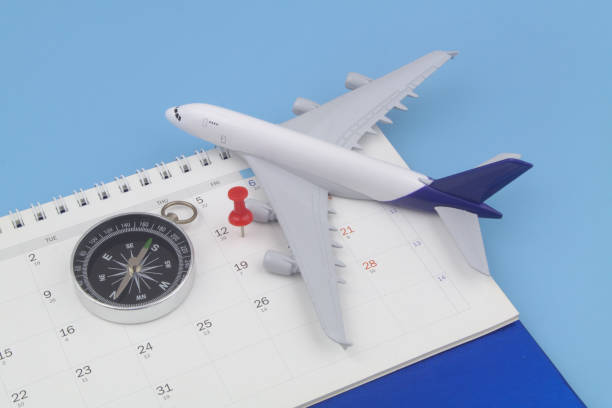 istock Airplane model with black compass and push pin on calendar page. 1372919192