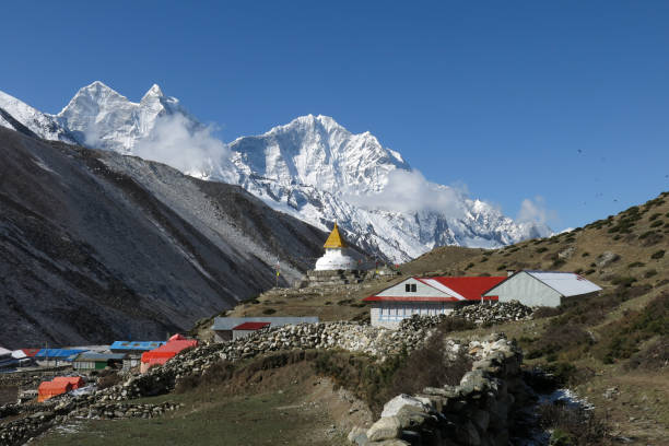 Stupa in the Sherpa village Dingboche and snow covered mountain Thamserku. stock photo