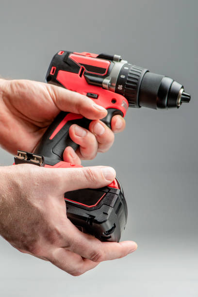 istock a man's hand removes the battery from a cordless tool. A man inserts a battery into a screwdriver. Repair and construction concept on gray background 1372920214