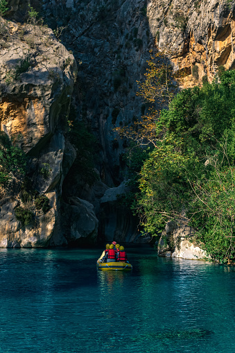 Antalya, Turkey - November 17, 2021: Tourists on an inflatable boat float down a rocky canyon with blue water in Goynuk, Turkey