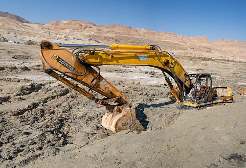 The dead sea, Israel - February 12th, 2022: A heavy excavator burnt after it was stranded forever in mud on the dead sea shore.