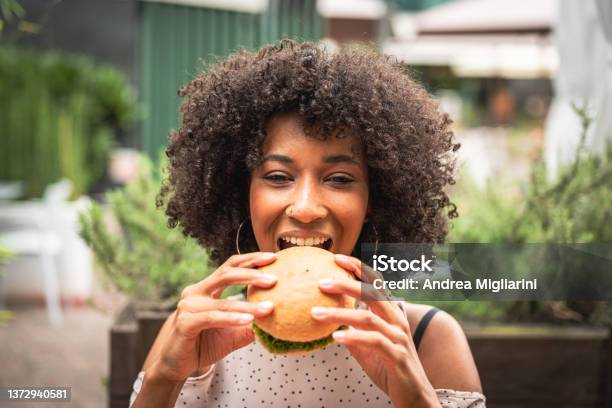 Young African Woman Enjoying Eating Veggie Burger At Restaurant Healthy Food And New Concept Of Habits And Feeding Stock Photo - Download Image Now