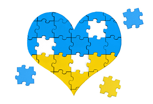Heart symbol made of jigsaw puzzle pieces painted the colors of the national flag of Ukraine and three pieces to be set in place isolated on white.