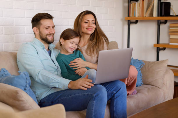 istock Smiling family relaxing at home and using laptop together 1372944929