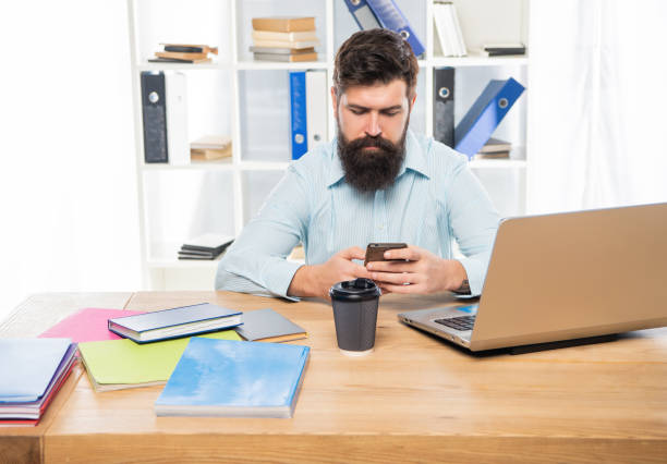 istock Serious businessman texting sms on mobile phone sitting at office desk 1372950996