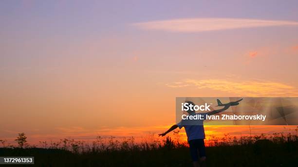 A Boy At Sunset Runs Across The Field In His Hands An Airplane The Kid Dreams Of Becoming An Astronaut Pilot Childhood Dream To Run With A Toy Pilot Of A Childrens Plane Dream Concept Stock Photo - Download Image Now