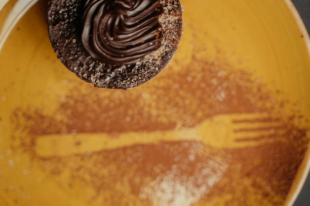 chocolate cupcake in black paper packaging, chocolate-drenched cupcake with chocolate flavor on a wooden table