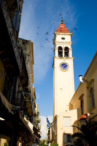 Greece - Corfu island - Corfu(Kerkira) town - Bell Tower of the Church of Saint Spiridon and flying birds. All birds in motion blur  - focus on clock.