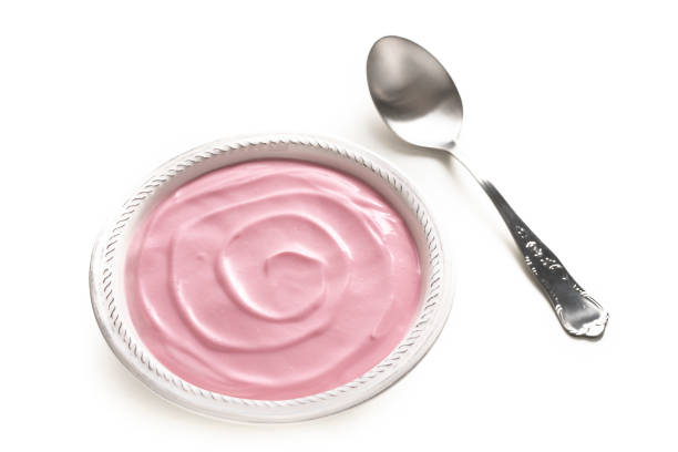pink fruit yogurt in a ceramic bowl with spoon on a light background, selective focus.