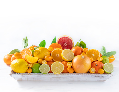 Assorted citrus fruits on white wood table background in a white crate wooden tray freshly harvest in Mediterranean area