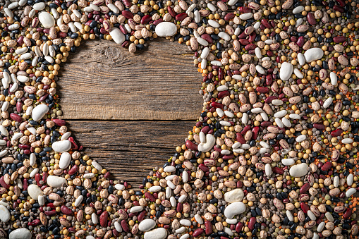 Legumes hearth shape with red beans in a mixed background of varied legumes mix as lentils chickpeas, beans and soybeans, as a healthy lifestyle eating concept