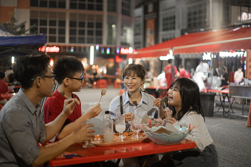 Asian Chinese family travelling, eating outdoor at night market