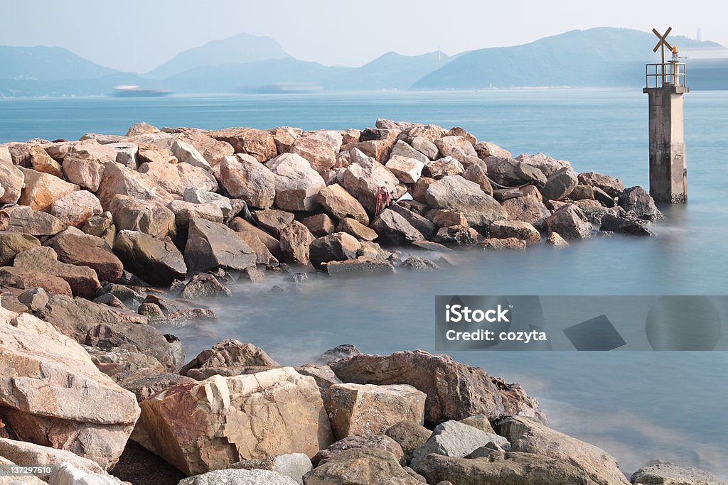 Lighthouse on a Rocky Breakwall Lighthouse on a Rocky Breakwall: A small lighthouse warns of a rough shoreline. Beach Stock Photo