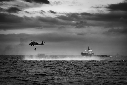 A US Navy MH-60 helicopter with a rescue swimmer trains close to a Japanese vessel off the coast near Yokosuka, Japan.