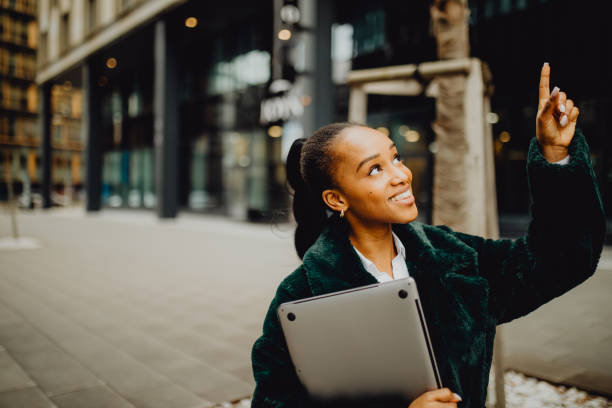 istock Smiling woman with laptop pointing up 1372977970