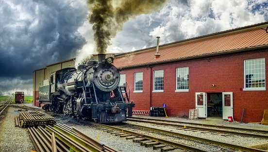 A Restored Steam Engine Getting Ready for Service, Blowing Smoke and Steam on a Cloudy Summer Day