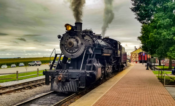 Restored Steam Engine Getting Ready for Service, Blowing Smoke and Steam A Restored Steam Engine Getting Ready for Service, Blowing Smoke and Steam on a Cloudy Summer Day locomotive stock pictures, royalty-free photos & images