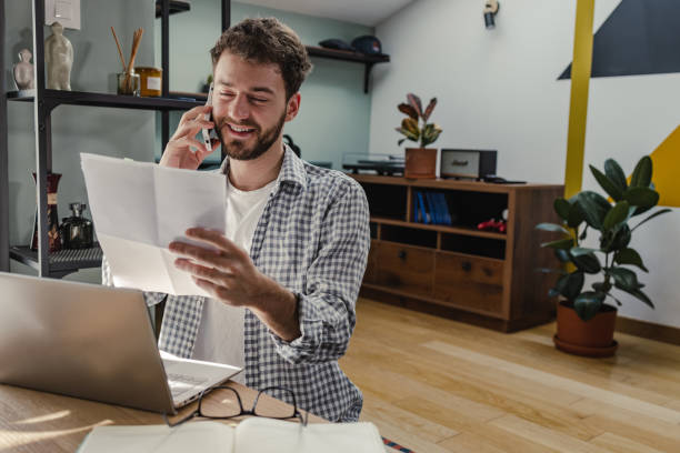 istock Working on laptop at home talking on the phone 1372981371