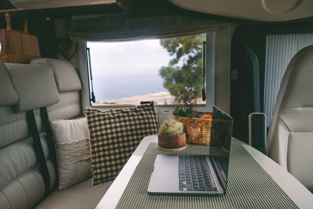 istock Travel lifestyle and online digital nomad workplace inside modern camper van. Laptop computer on the table and nature outside the window view. Roaming connection internet and remote worker job 1372982649