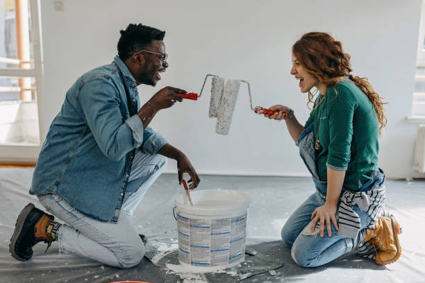 istock Young  couple painting wall and play with paint roller 1372984802