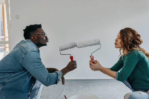 istock Young  couple painting wall and play with paint roller 1372984836