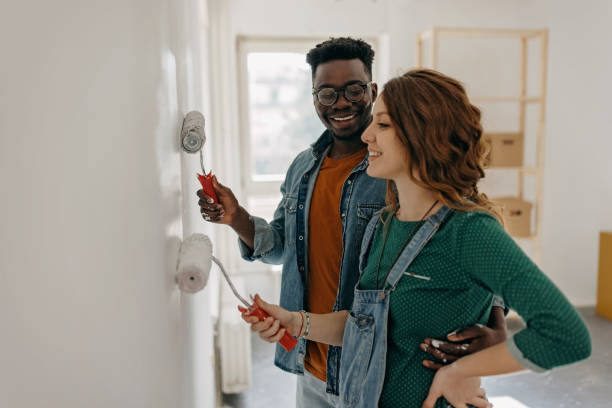 jeune couple peignant des murs - redecoration photos et images de collection