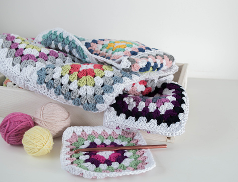 colorful granny square pattern with crochet hook and woolen balls in wooden box hobby handmade