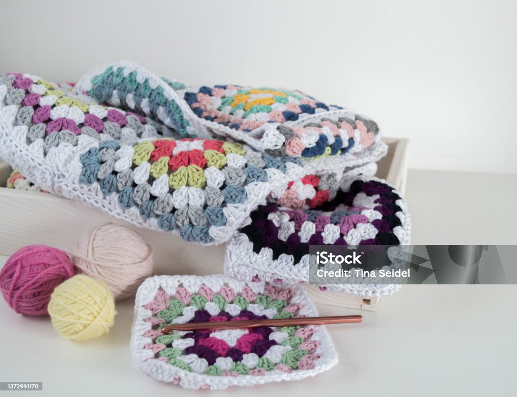 colorful granny square pattern with crochet hook and woolen balls in wooden box colorful granny square pattern with crochet hook and woolen balls in wooden box hobby handmade Crochet Stock Photo