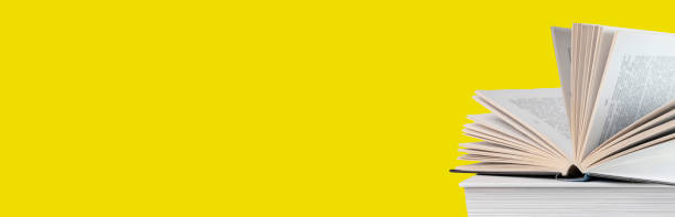 istock Banner with open book lying at books stack on yellow background. Reading and turning pages. Education and getting knowledge concept 1372998148